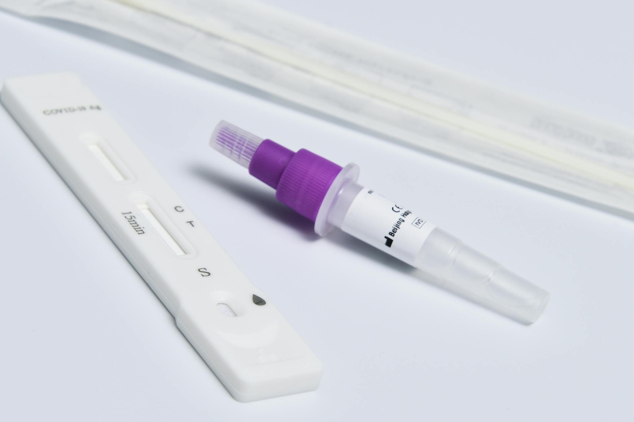 Close-up of a COVID-19 rapid antigen test kit with a dropper and swab on a white surface.